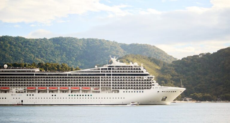 A majestic cruise ship sails through tranquil waters with lush hills in the background, perfect for travel enthusiasts.